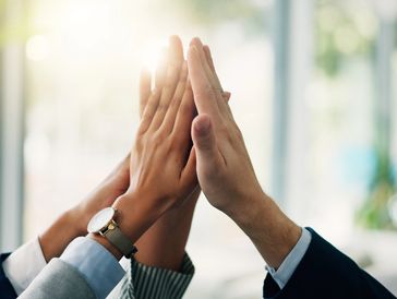 Group high five in a business setting.