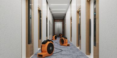 A row of industrial air movers with wide, circular vents in a commercial building.