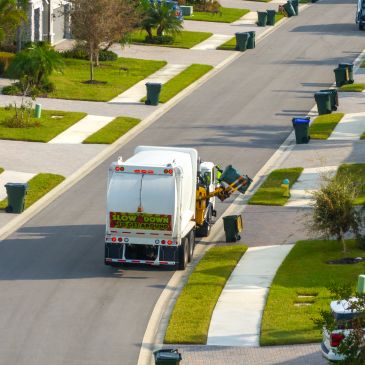 Garbage truck collecting trash in a suburban neighborhood.