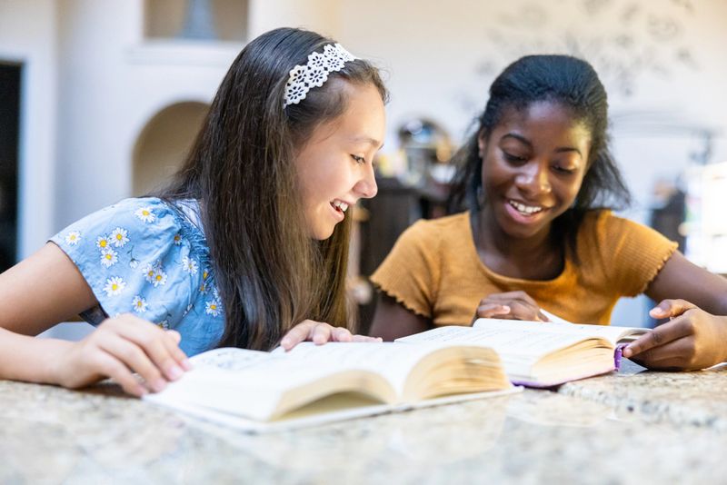 Two middle school aged girls reading in the library