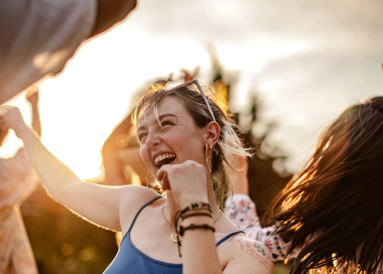 Young woman smiling and enjoying a sunny outdoor moment with friends.