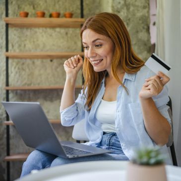 Happy woman shopping online with credit card and laptop.
