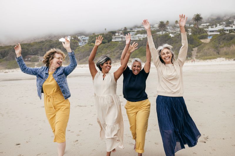 Unexpected Benefits of Friendship . Four women in their 50-60 together on a walk in a misty beach