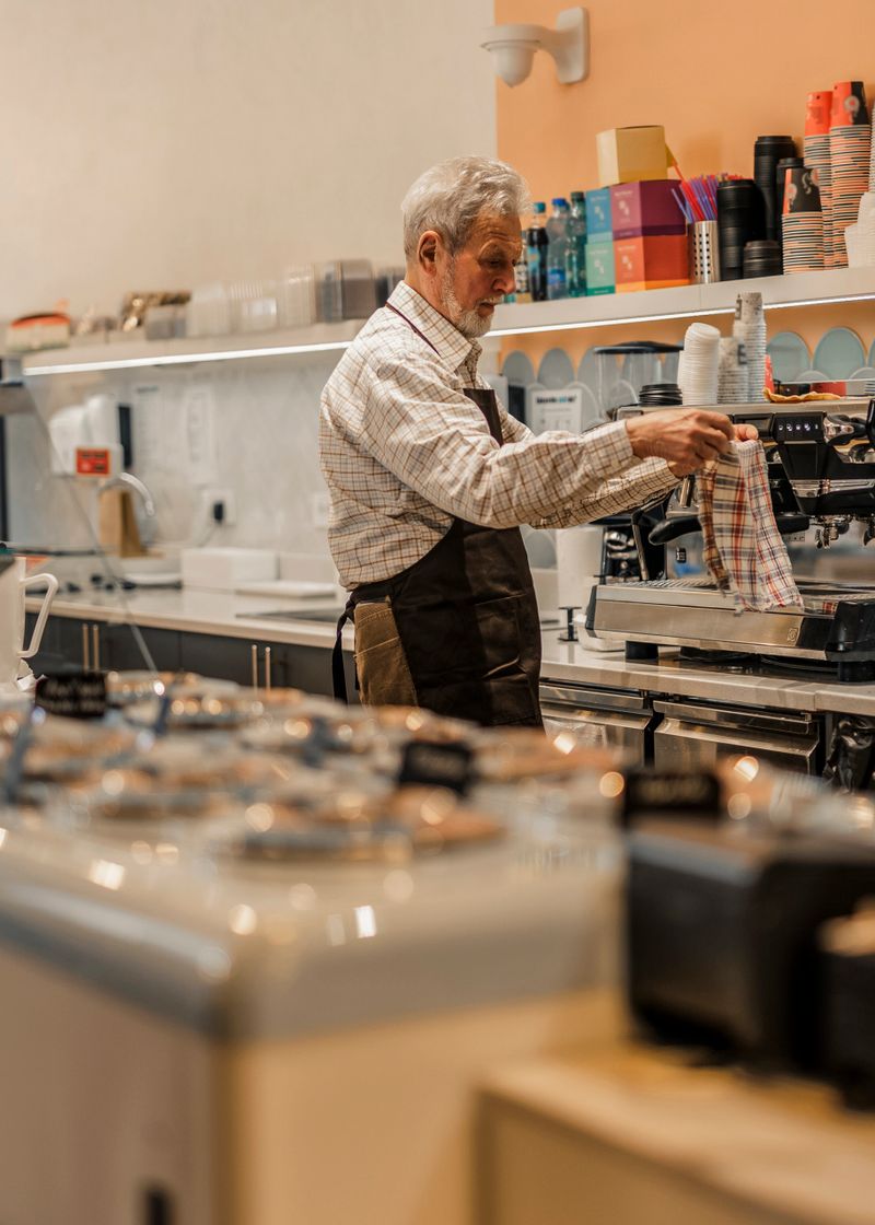 Smiling male barista preparing cappuccino in a coffee shop