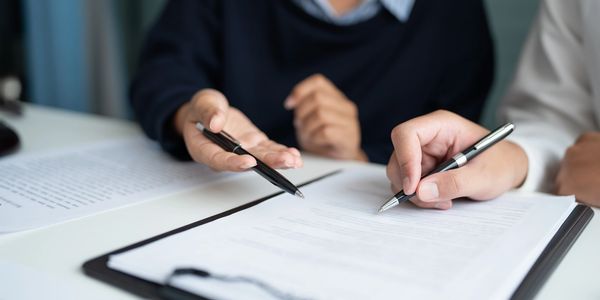 Two people reviewing and discussing documents at a desk.