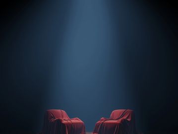 Two chairs covered with red cloth under a spotlight.
