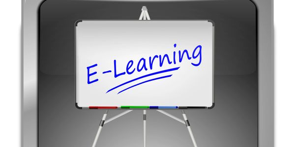 Whiteboard with "E-Learning" written in blue marker.