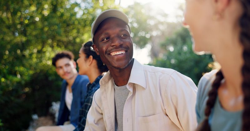 Camping, couple and friends in woods, relax and bonding on adventure with group, outdoor and smile. Happy, travel and people in forest for holiday, men and conversation with women on double date