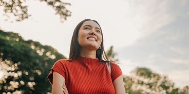 Smiling young woman outdoors in a red top.