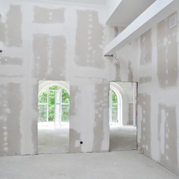 A room under construction with unfinished drywall and exposed wiring.