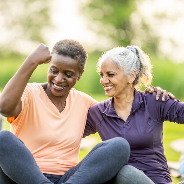 Two happy women celebrating fitness success outdoors.
