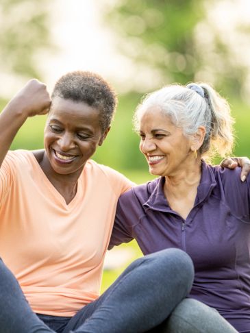 Two women smiling and celebrating outdoors.