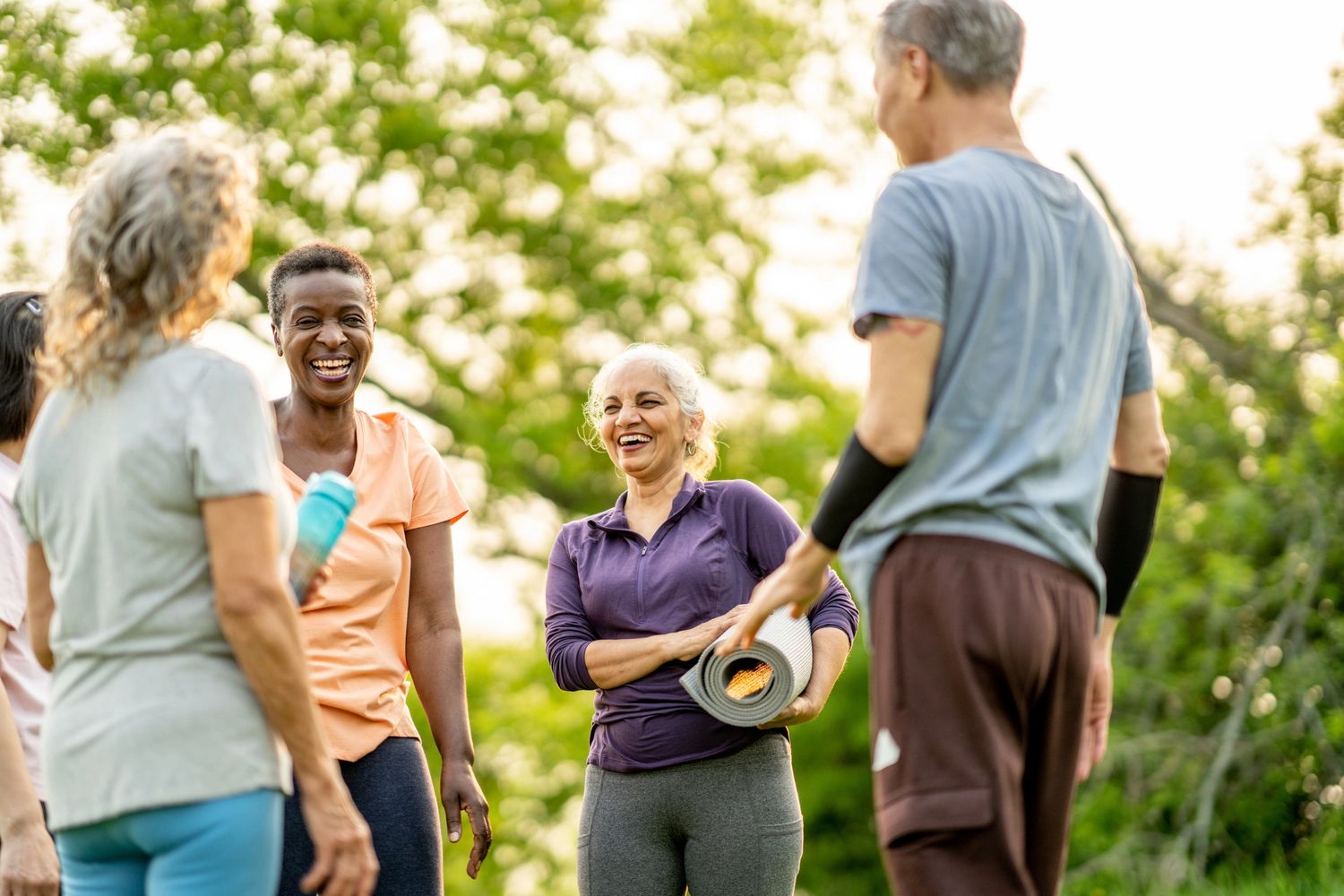 A group of diverse seniors enjoying a sunny outdoor yoga session.