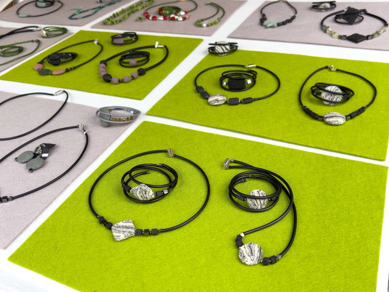 Handcrafted stone jewelry display with necklaces, bracelets, and earrings on felt mats, lifestyle