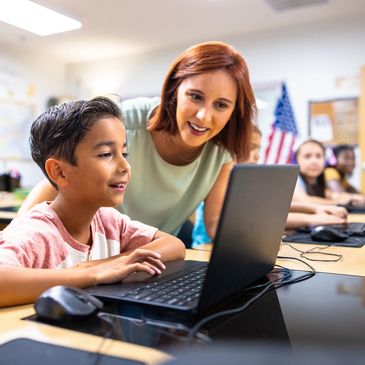 Woman wearing headphones smiling while working on a laptop at home.