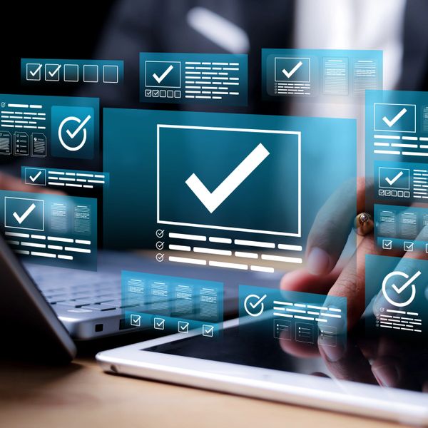 Digital checklists and approvals displayed over a tablet and laptop workspace.
