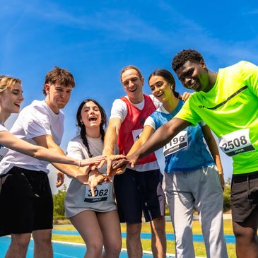 A group of runners joining hands in team spirit before a race.