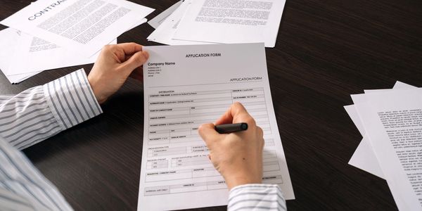 Person filling out an application form at a desk.