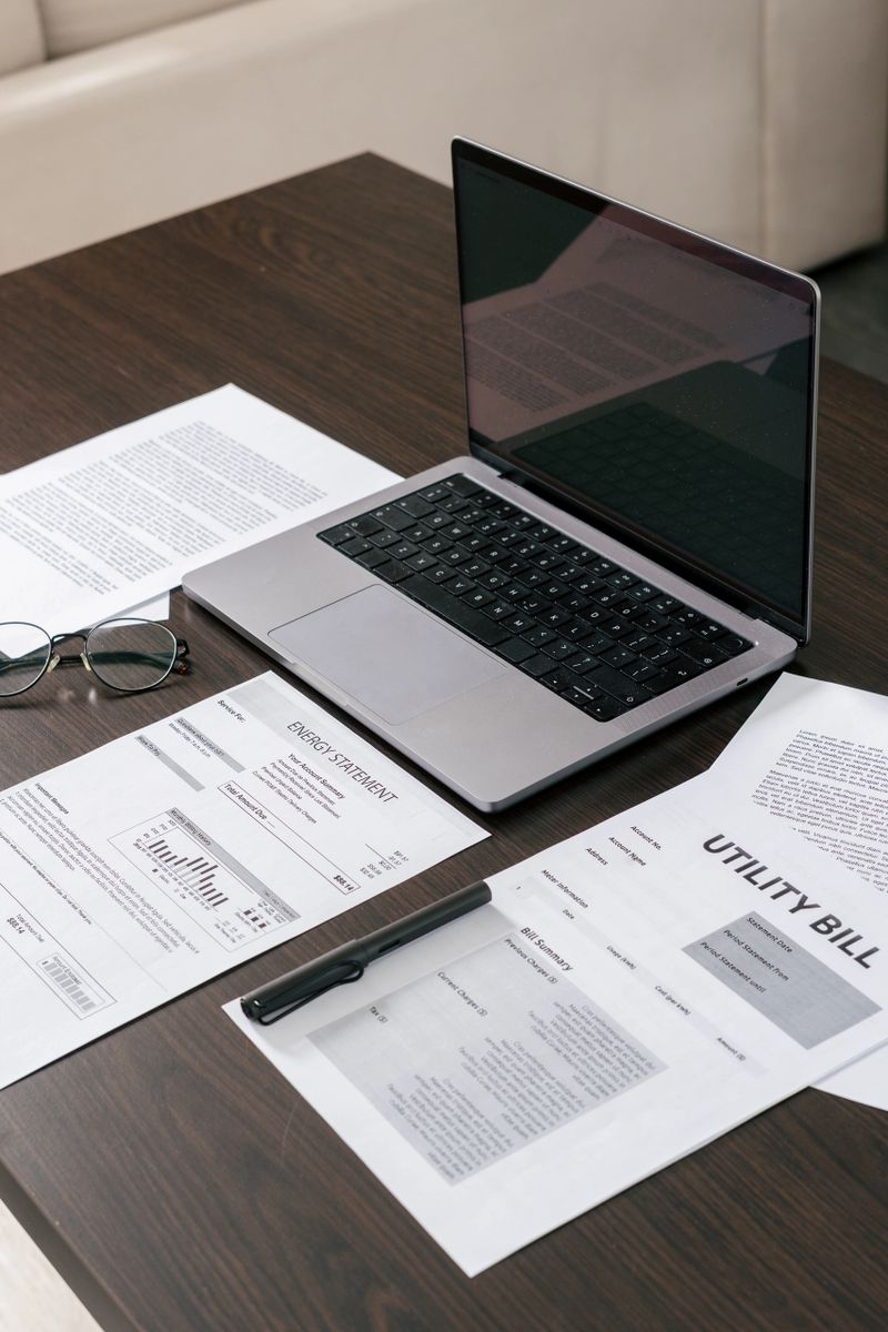 Financial bills are neatly organized on desk alongside a laptop. Concept of paying for electricity and utilities, debt, bank statements, housing loan, budget planning