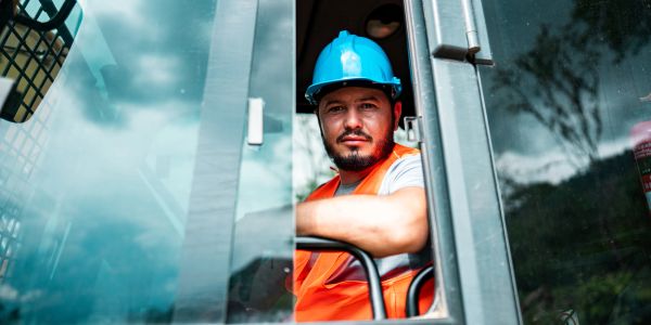 Construction worker wearing a blue helmet and orange vest.