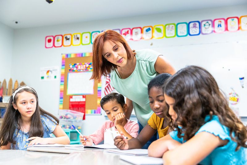 Young female teacher working with her students on a writing lesson in school