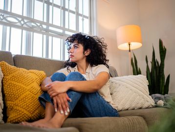 Woman sitting pensively on a couch.