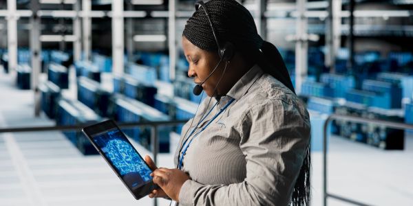 Woman with headset using a tablet in a large warehouse.