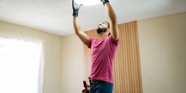 Man replacing a ceiling light bulb.