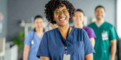 Smiling medical team with focus on a female nurse in blue scrubs.