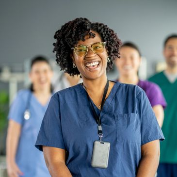 Healthcare professional wearing blue scrubs with a red stethoscope around the neck.