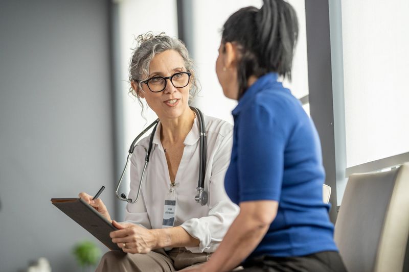 Medical practitioner discussing healthcare concerns with a patient in a modern clinic environment, ensuring comfort and understanding during their consultation.