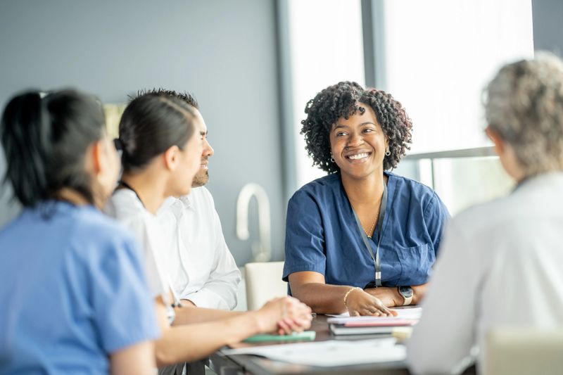 Healthcare professionals gather informally around a table, brainstorming, sharing insights, and working collaboratively in a bright office environment, showcasing teamwork, professionalism, and diversity in the medical field.