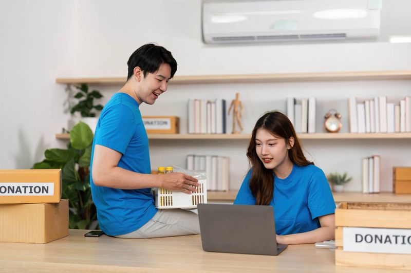 Two enthusiastic volunteers work together to prepare donation items, highlighting teamwork and community involvement.