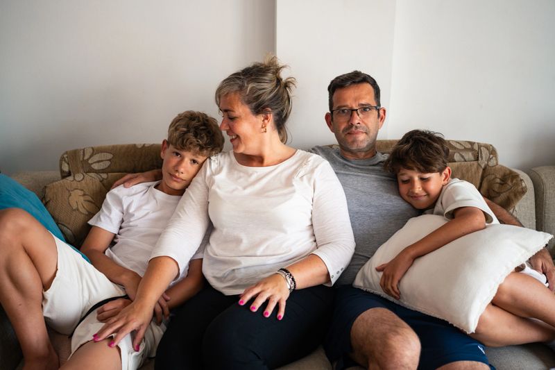 Portrait of a family with two teens relaxing on a couch in a cozy living room during the afternoon. The atmosphere is warm and inviting.