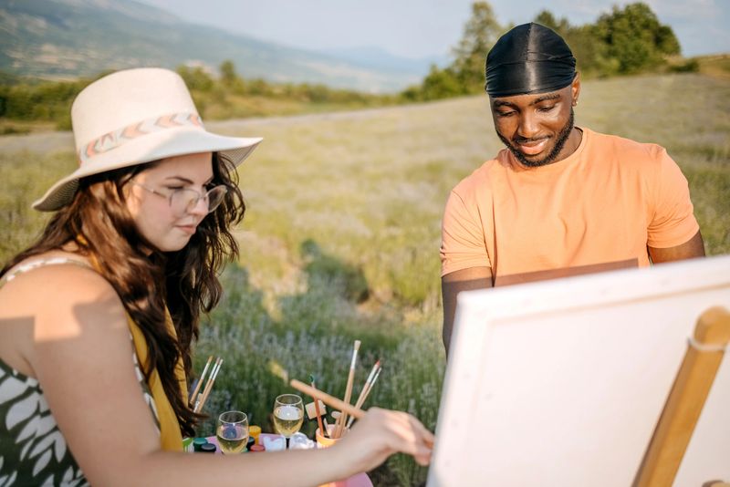 Young adults creating painting while standing in lavender field in nature and supporting each other