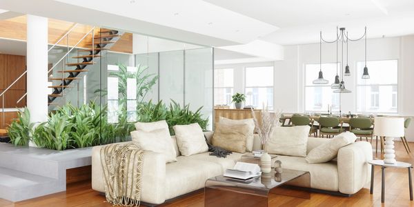 Bright modern living room with beige sofas, indoor plants, and wooden accents.