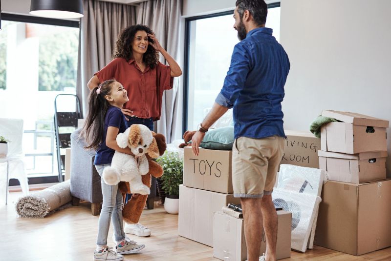 A cheerful family moves into their new home, unpacking boxes with shared excitement and joy. The image captures a heartwarming moment of unity during a significant milestone.