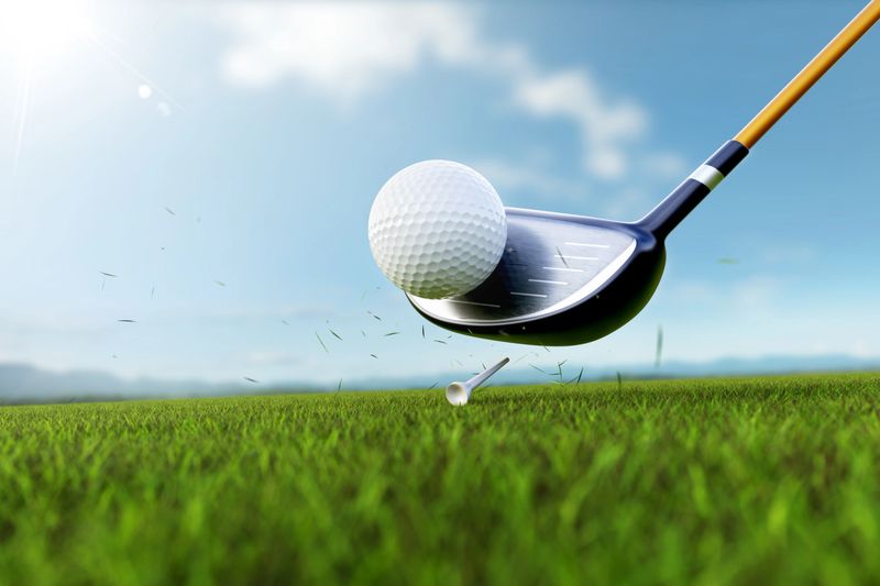 golf club hitting a ball on a tee, captured at the moment of impact with grass flying around. dynamic action metaphor precision and power in sports.