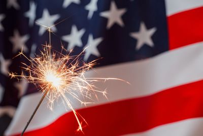 US flag in the background with sparkler in the foreground