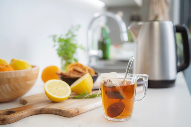 Hot herbal tea served in a glass cup on kitchen counter, Healthy detox brevage, citrus fruits and kettle to start the day with vitality