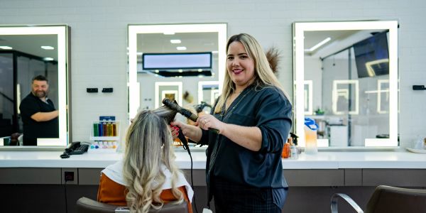 Hairdresser styling client's hair in a salon.