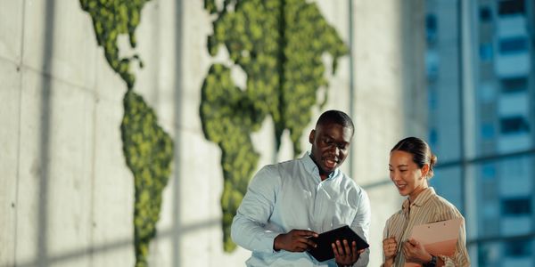 Two professionals discussing work using a tablet in a modern office.