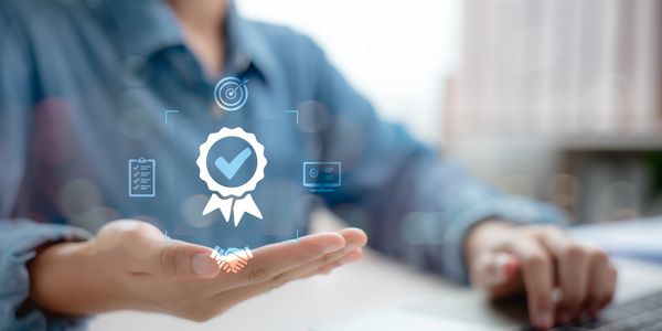 Person presenting quality assurance and success icons with a laptop.