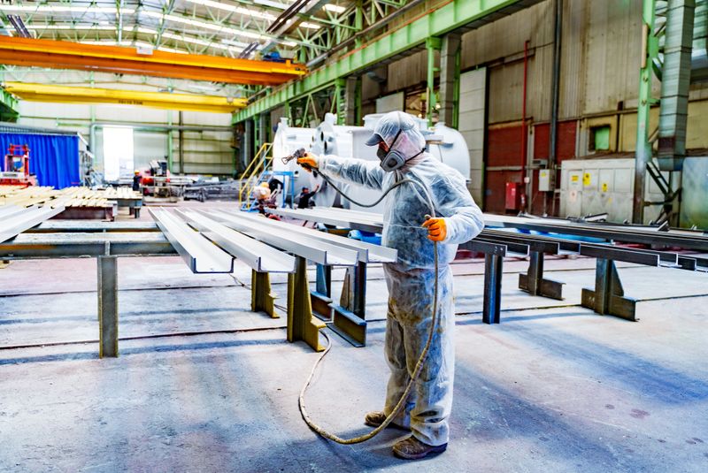 A painter is painting a steel surface white