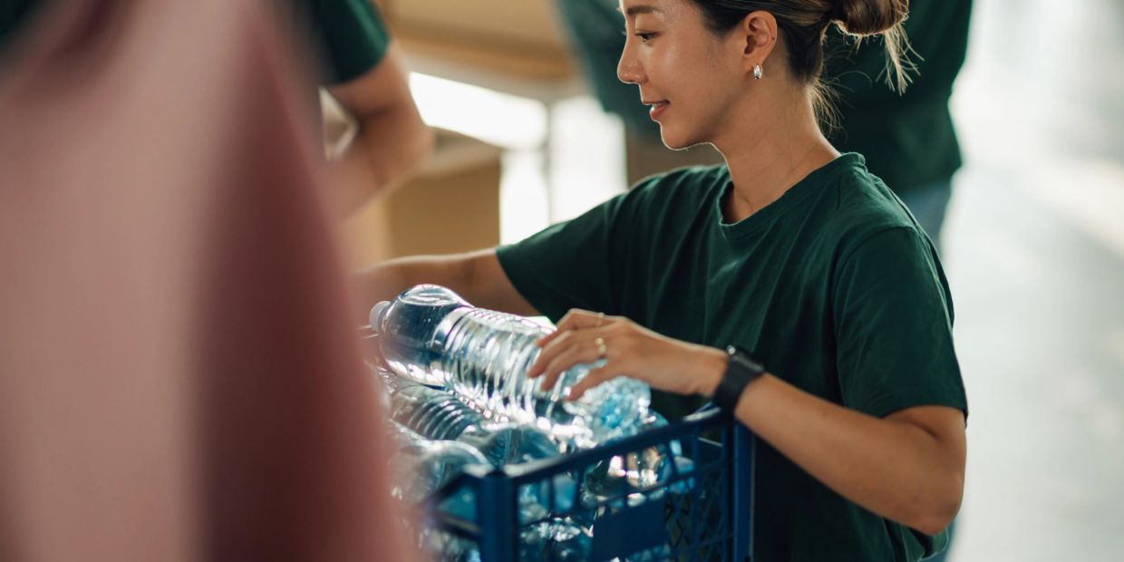 Woman sorting water bottles into a crate.