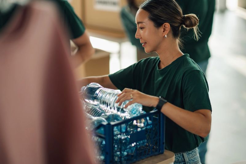 Young adult woman actively sorting plastic bottles for recycling at a community center, contributing to sustainability and environmental protection