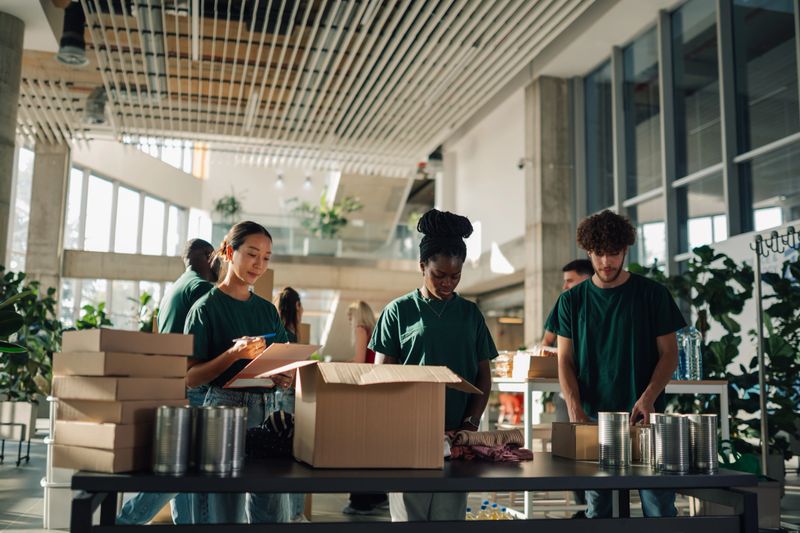 Volunteers sorting and packing food and clothing donations at a community center, fostering generosity and support within the community