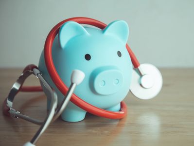 Blue piggy bank with a red stethoscope around it.