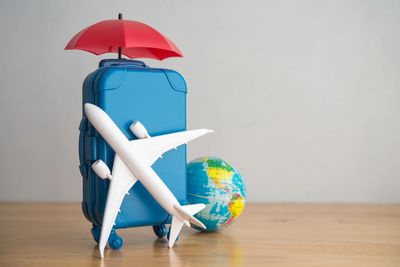 Travel-themed with suitcase, airplane, umbrella, & globe – CPA guidance on deductible travel expense.