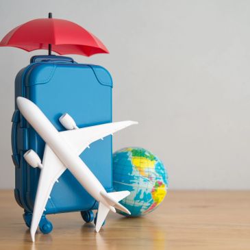 Travel essentials with umbrella, suitcase, toy plane, and globe.
